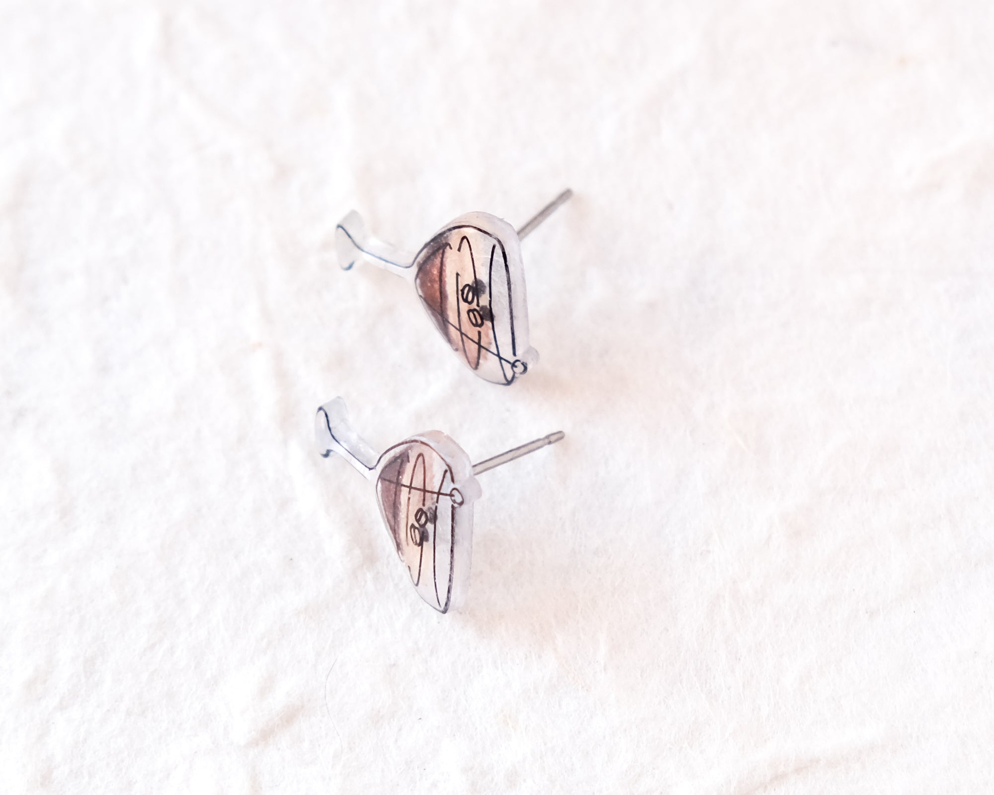 a pair of earrings with a unique design, resting on a white surface.
