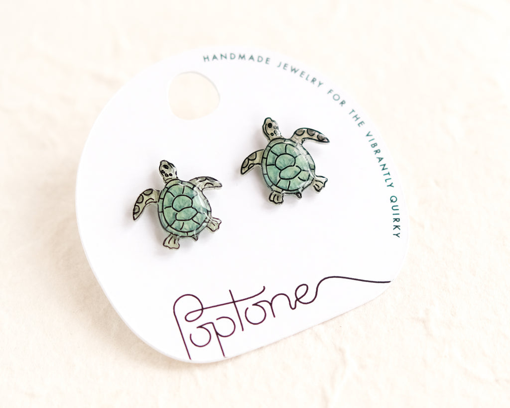 a pair of sea turtle earrings on a white background