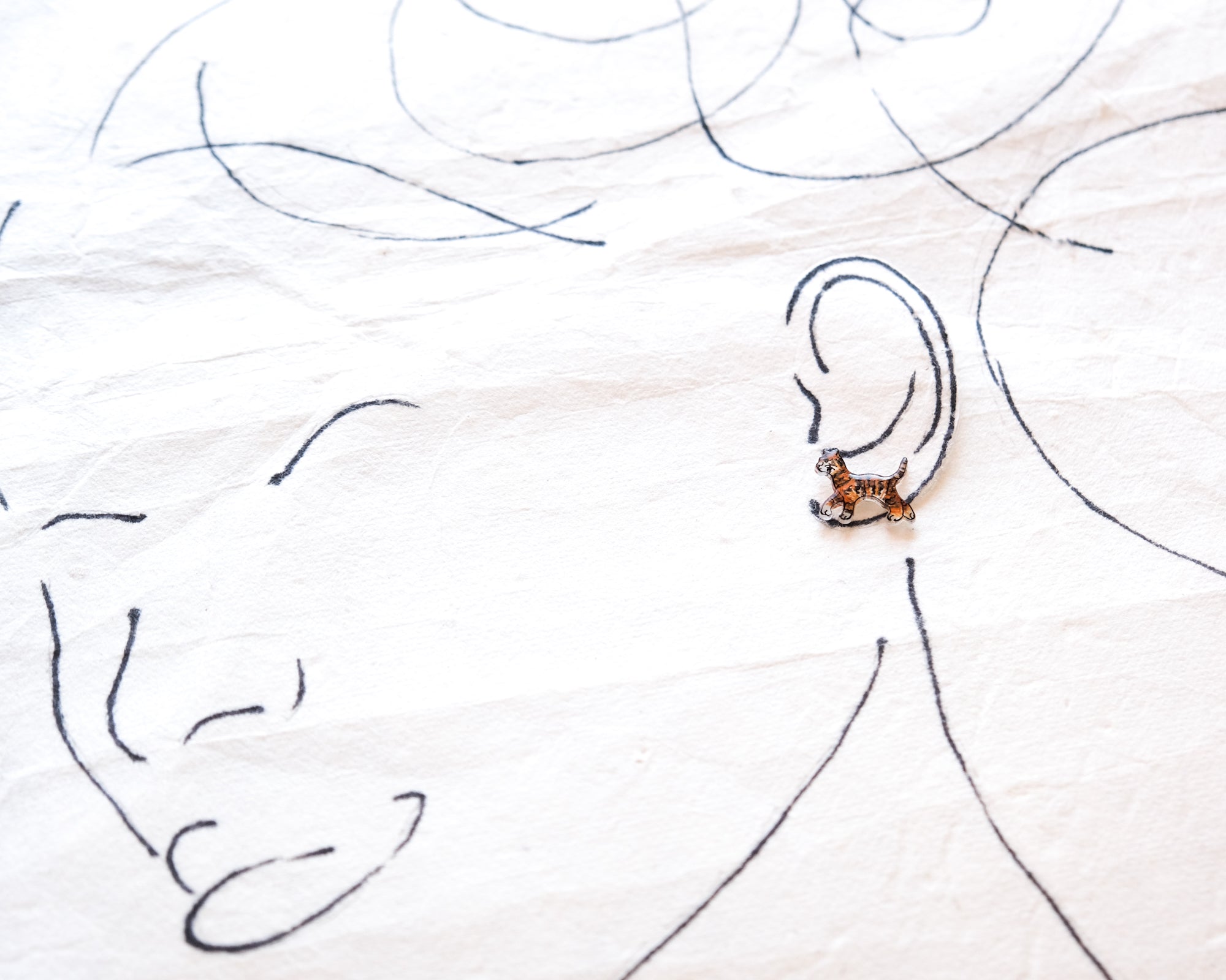 a close-up view of a person's face with a small tiger-like figure on their ear.