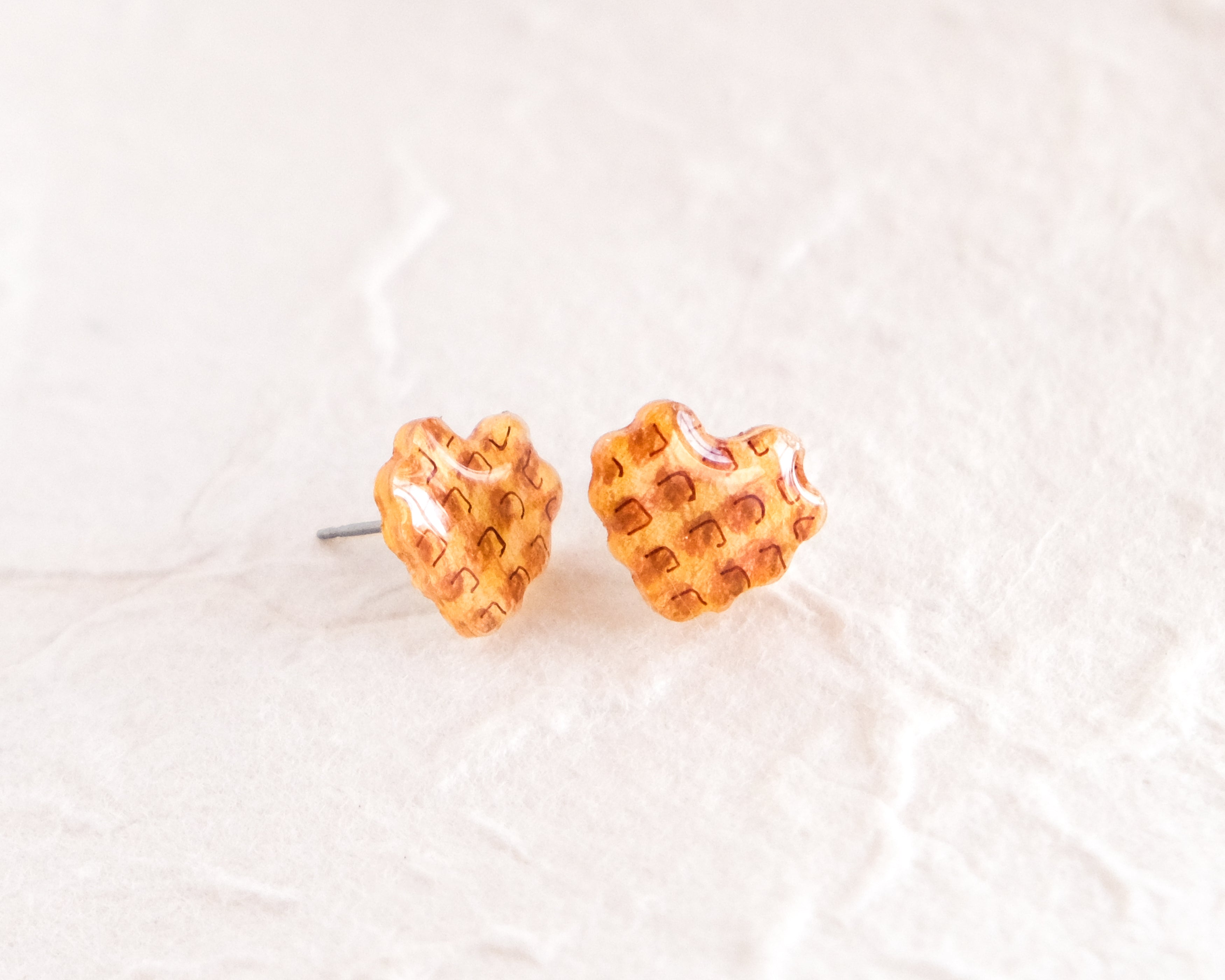 a pair of heart shaped earrings sitting on top of a white surface