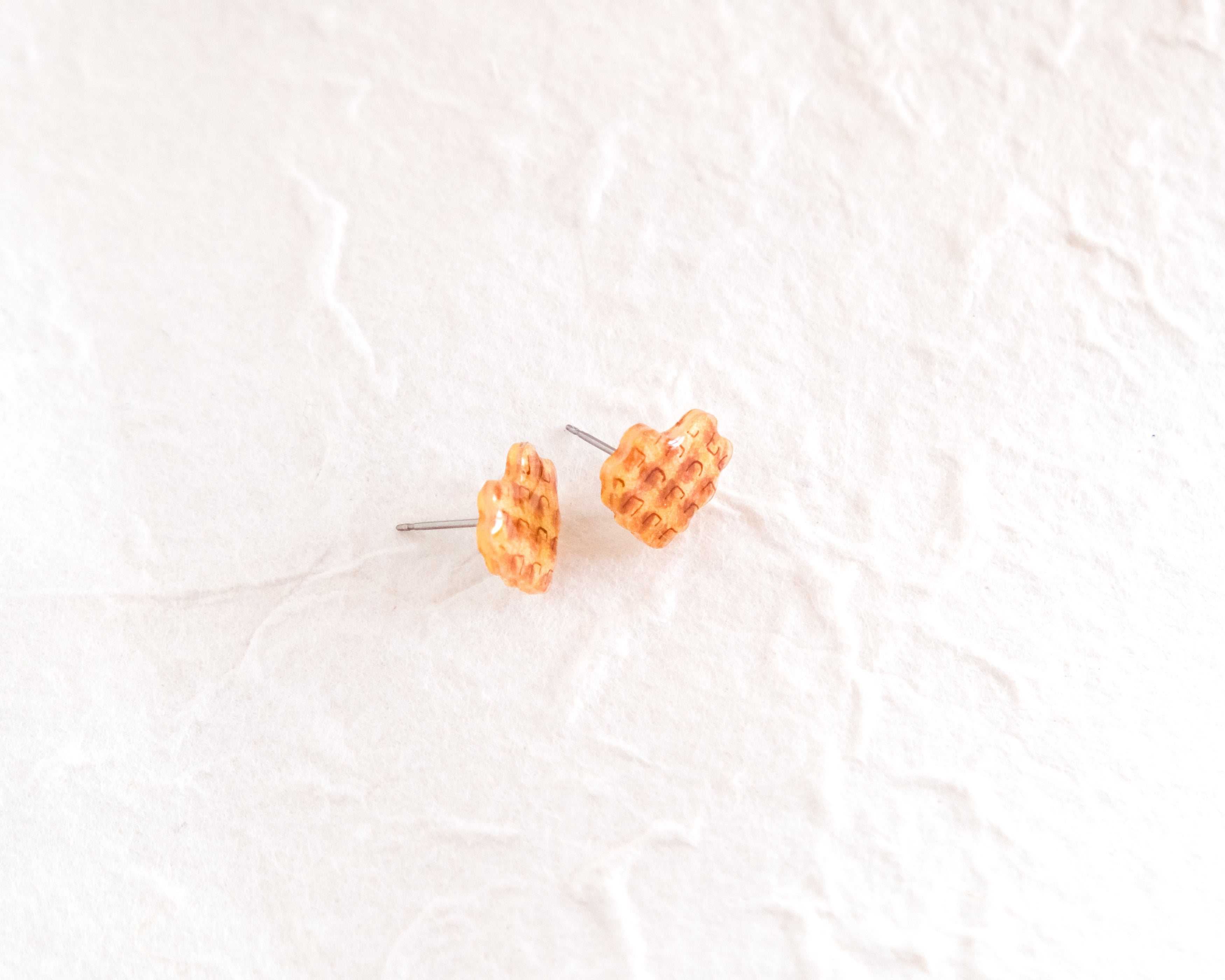 a pair of yellow checkered earrings on a white surface