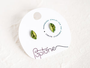 a pair of green earrings sitting on top of a piece of paper