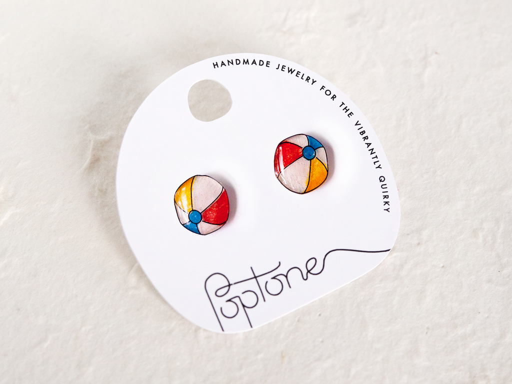 a pair of colorful earrings sitting on top of a white tag