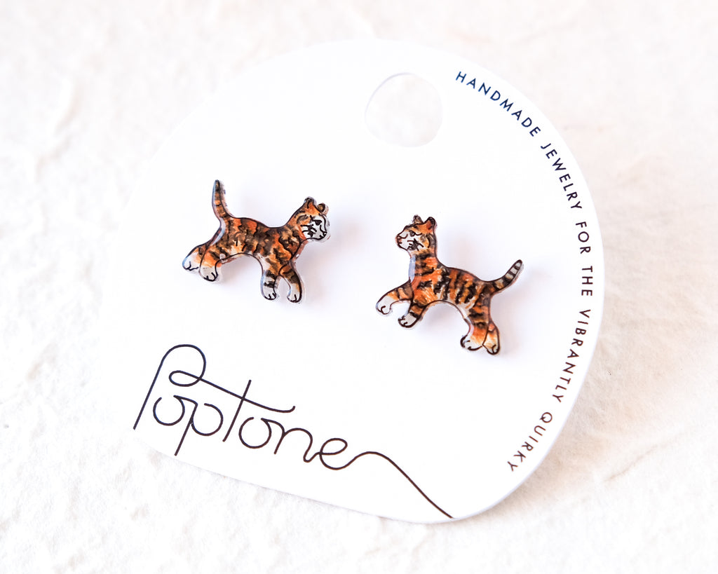 a pair of earrings in the shape of tiger cats, displayed on a white background.