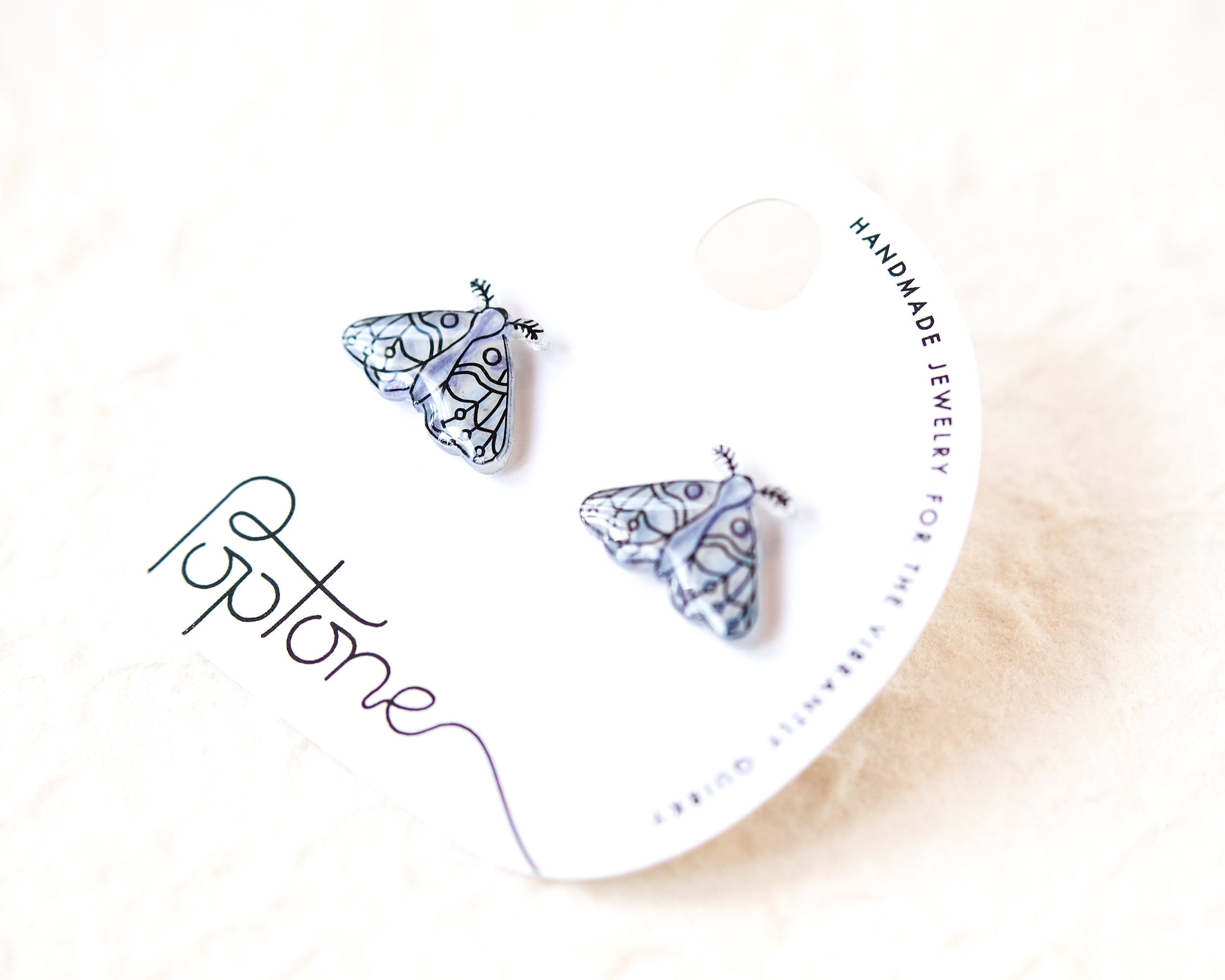 a pair of earrings with a butterfly design, placed on a white background.