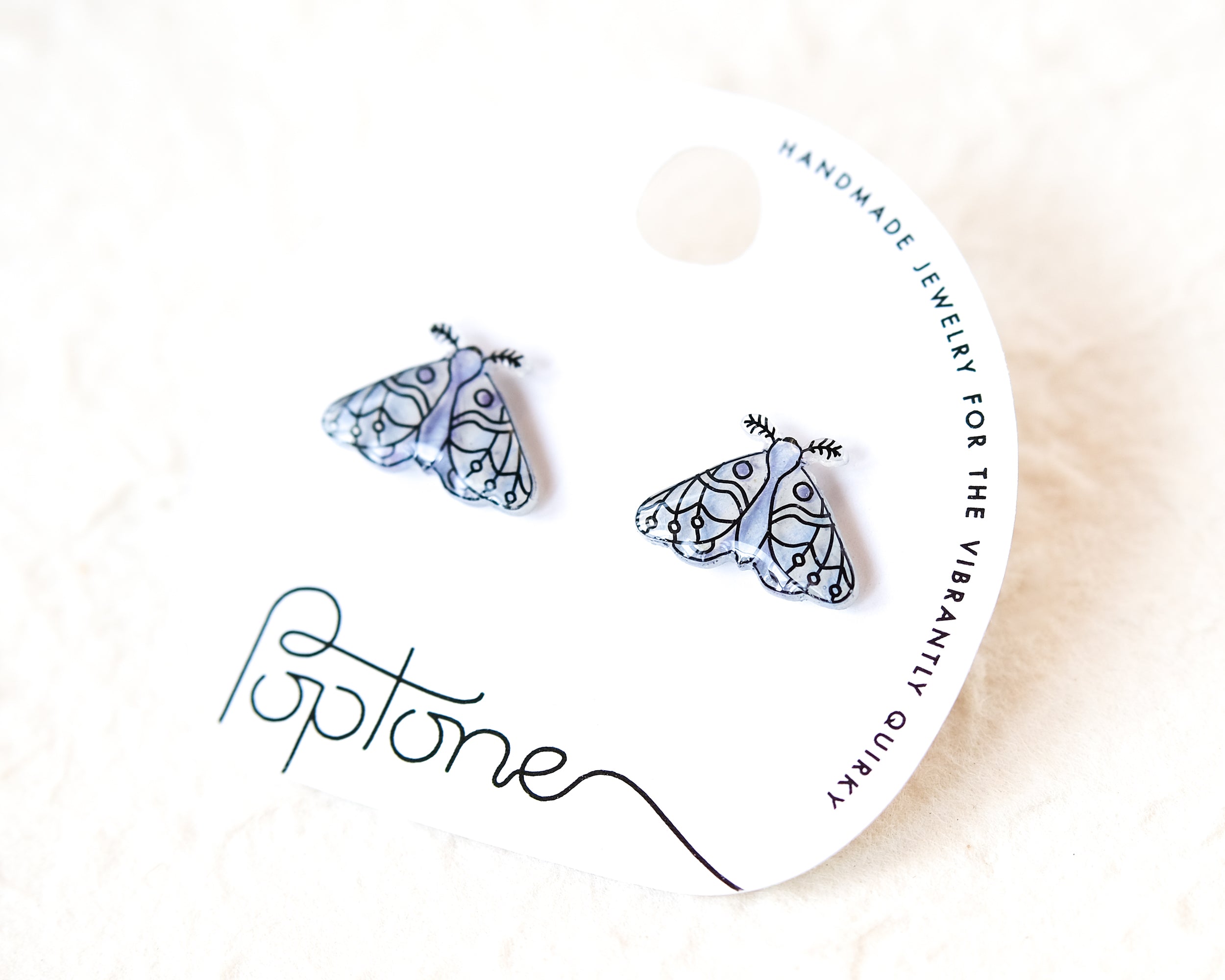 A pair of earrings with a butterfly design, presented on a white background with a black and white text label.
