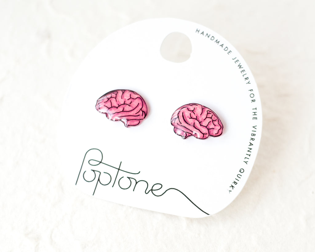 a pair of pink brain earrings sitting on top of a white surface