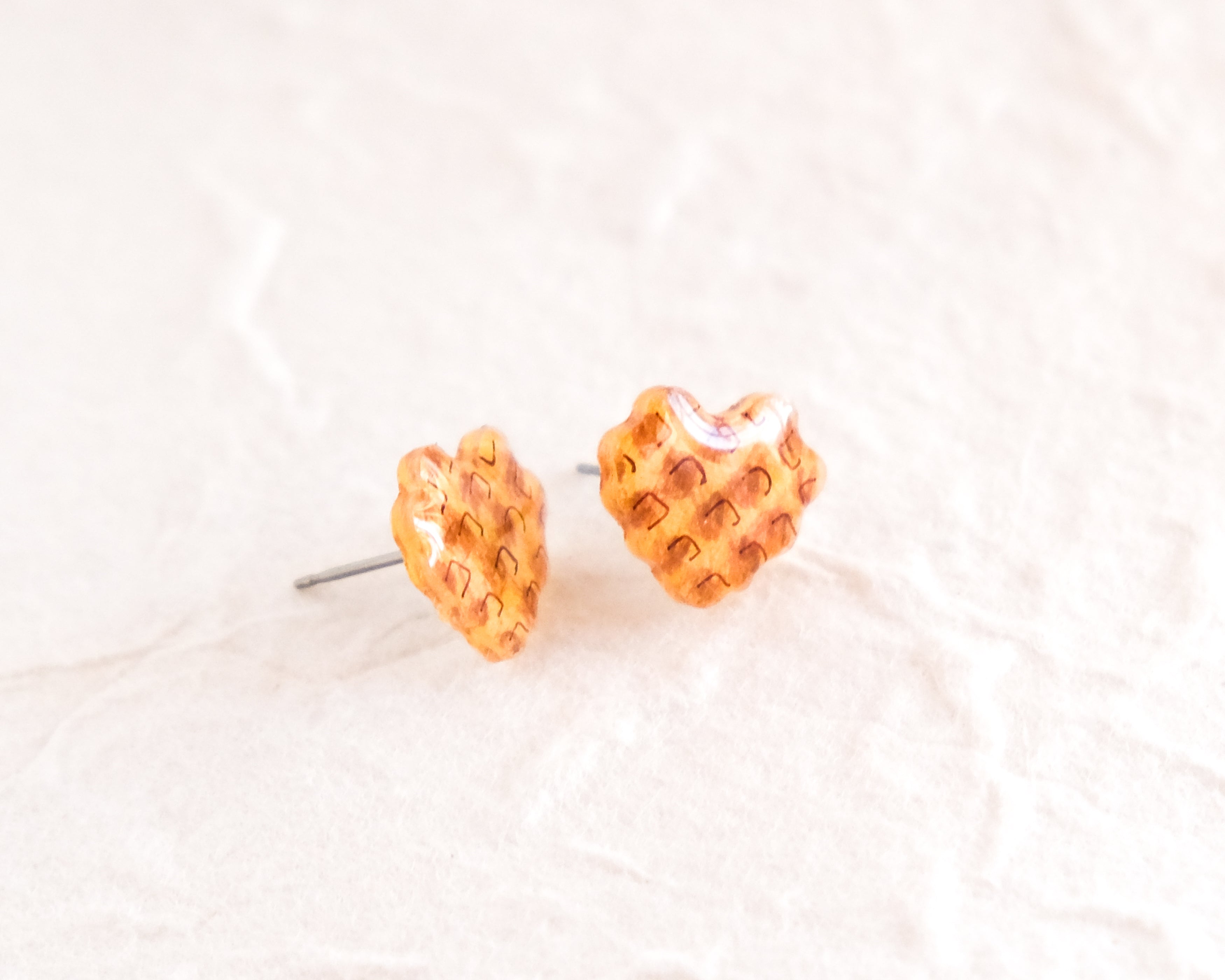 a pair of yellow heart shaped earrings on a white surface