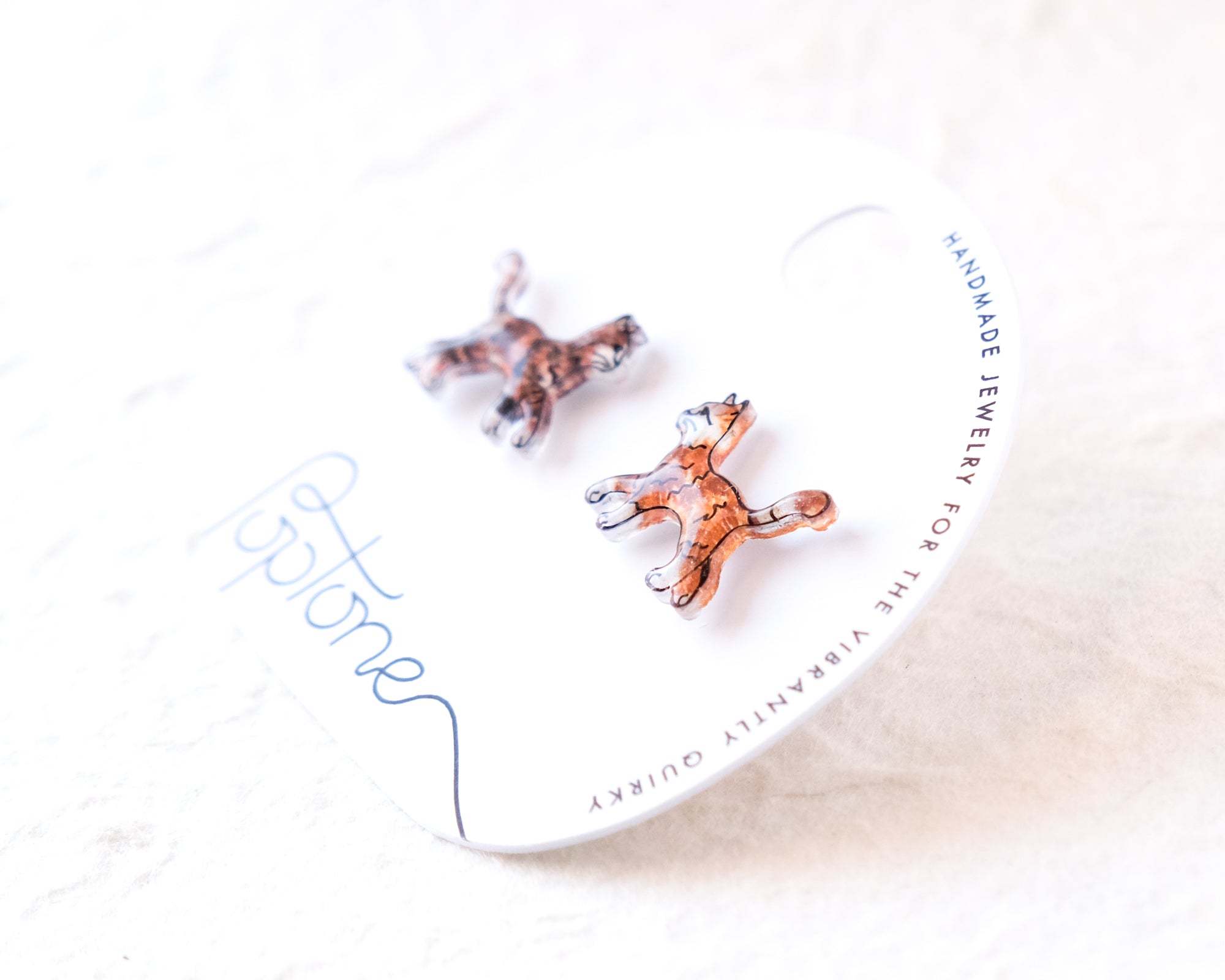 a pair of earrings, one in a brown color and the other in a clear color, placed on a white surface.