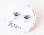 Load image into Gallery viewer, a pair of earrings with a design of two martini glasses, each containing a small black object, placed on a white background.
