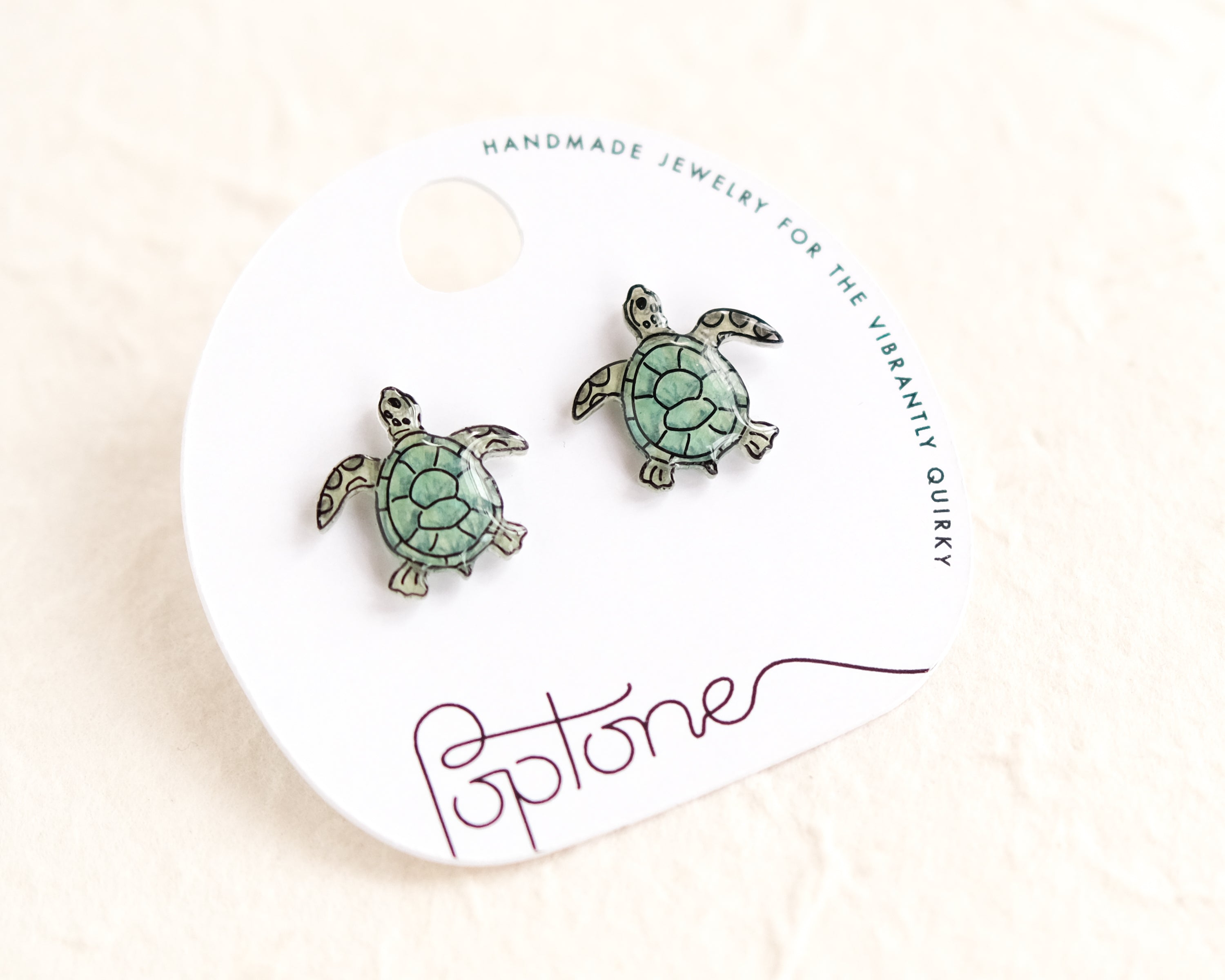 a pair of sea turtle earrings on a white background