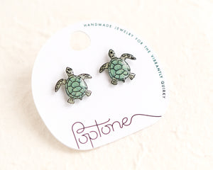 a pair of sea turtle earrings on a white background