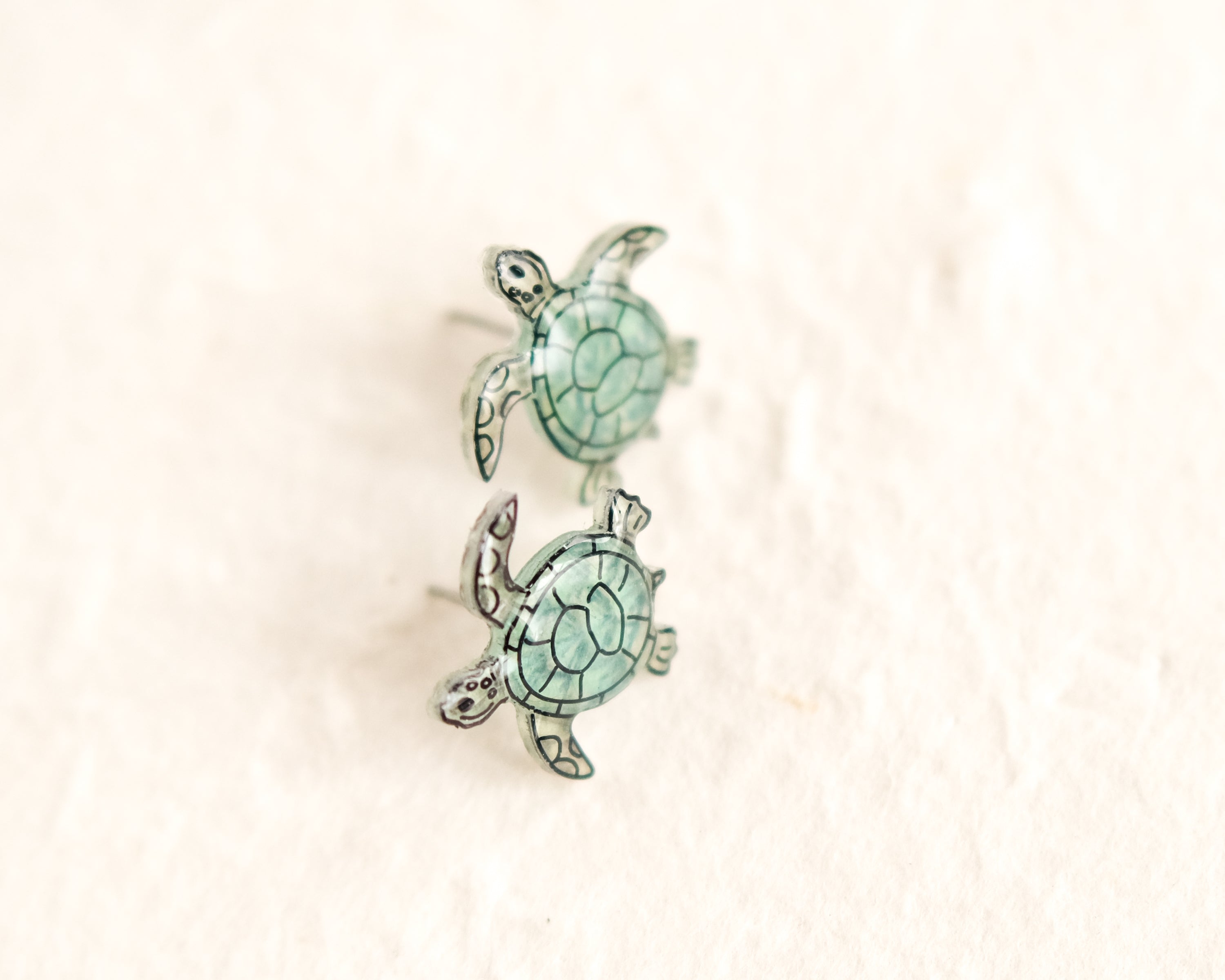 a pair of sea turtle earrings sitting on top of a white surface