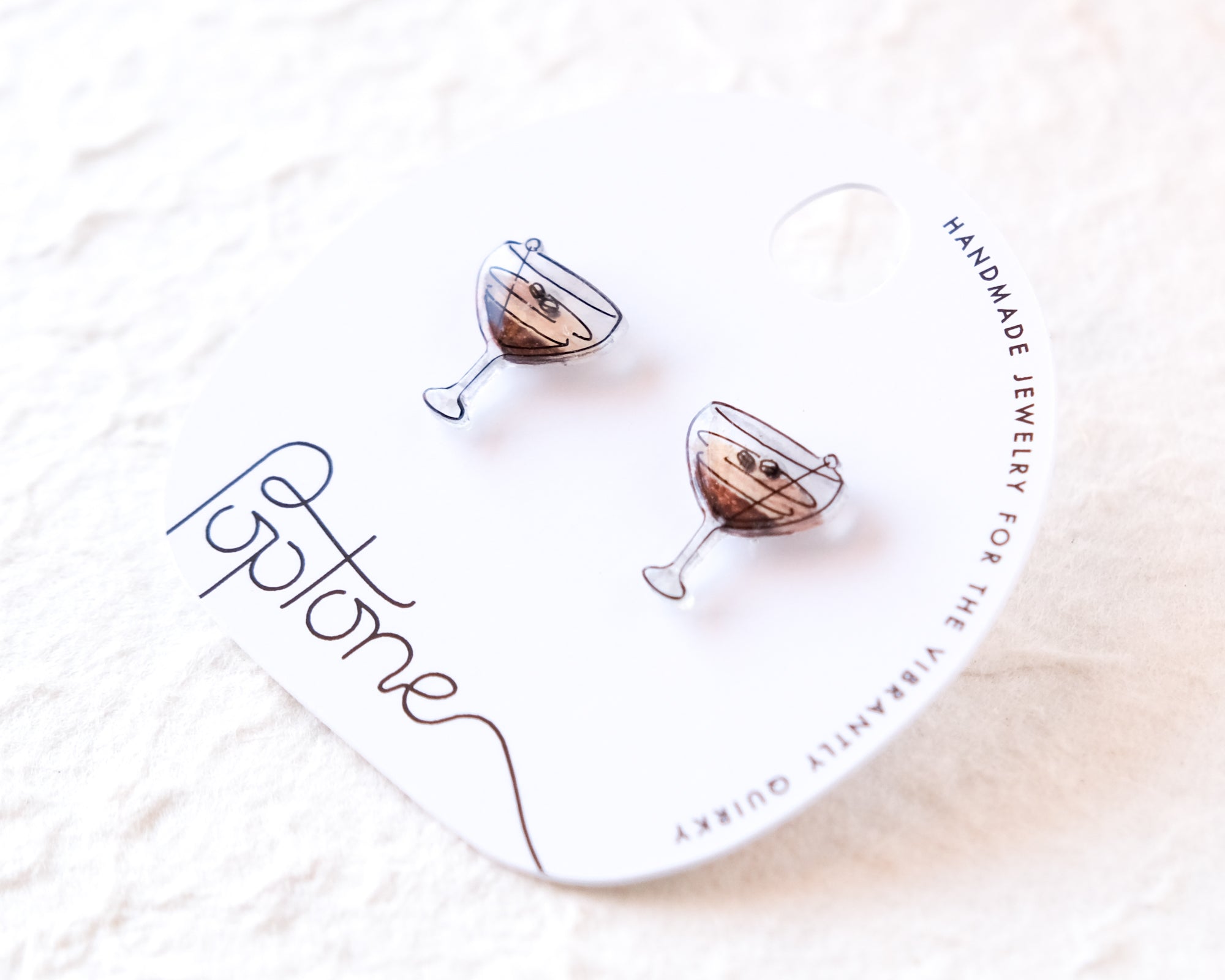 a pair of earrings with a design of wine glasses on a white background.