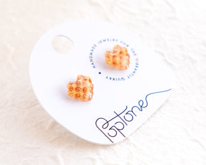 a pair of orange earrings sitting on top of a white table