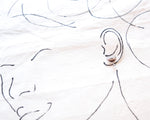 Load image into Gallery viewer, a close-up view of a pair of earrings, with the earrings being the main focus. The earrings are positioned in the center of the image, drawing attention to them. The background is a white fabric with black lines, which adds depth and texture to the image. The overall composition is simple and minimalistic, with the earrings being the focal point.
