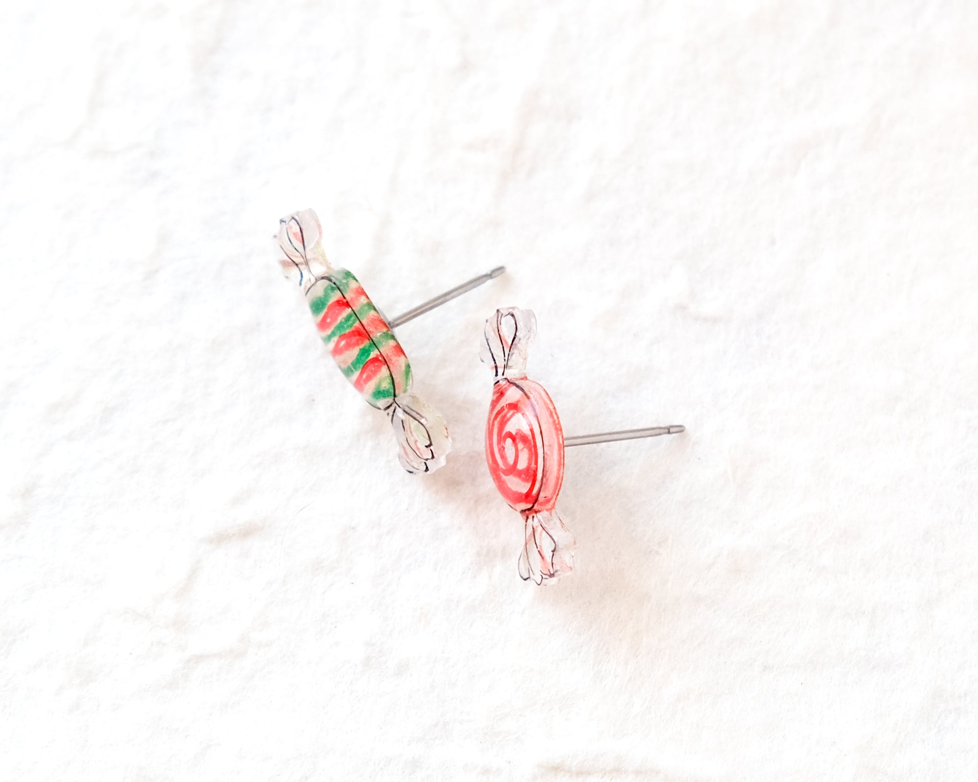 Two colorful candy-shaped earrings made of clear plastic and metal are shown against a white background.