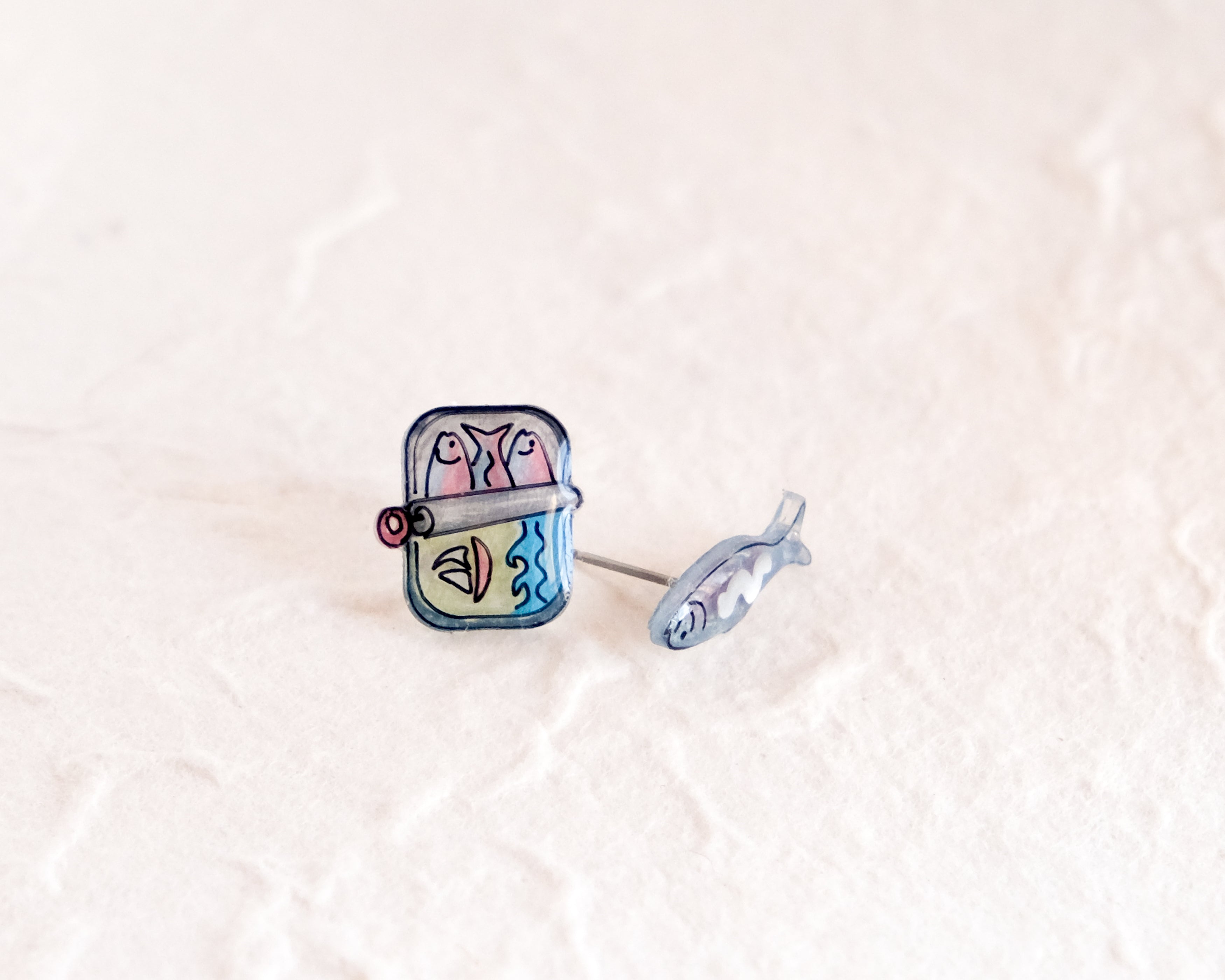 a pair of blue and pink earrings sitting on top of a white surface