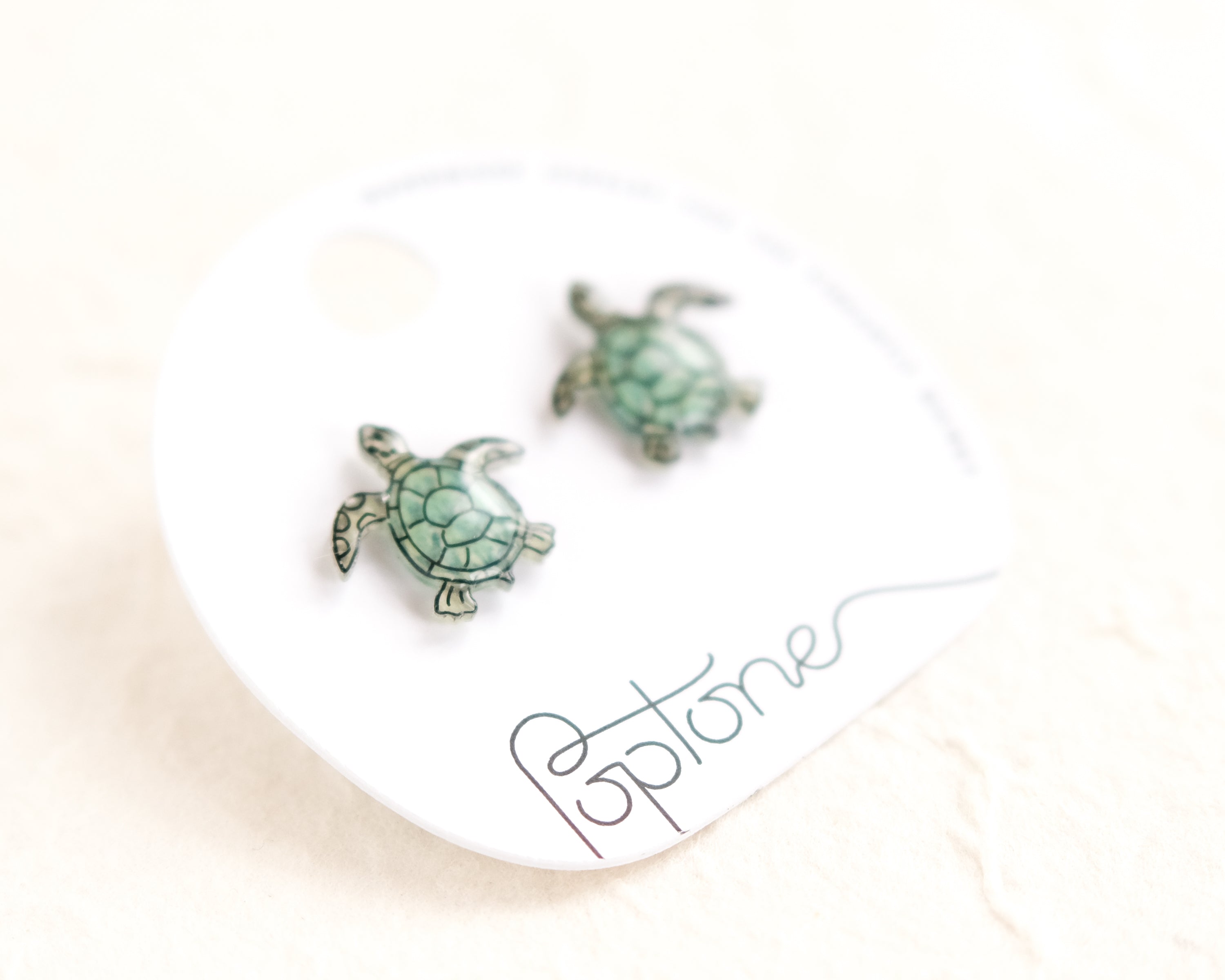 a pair of sea turtle earrings sitting on top of a white plate