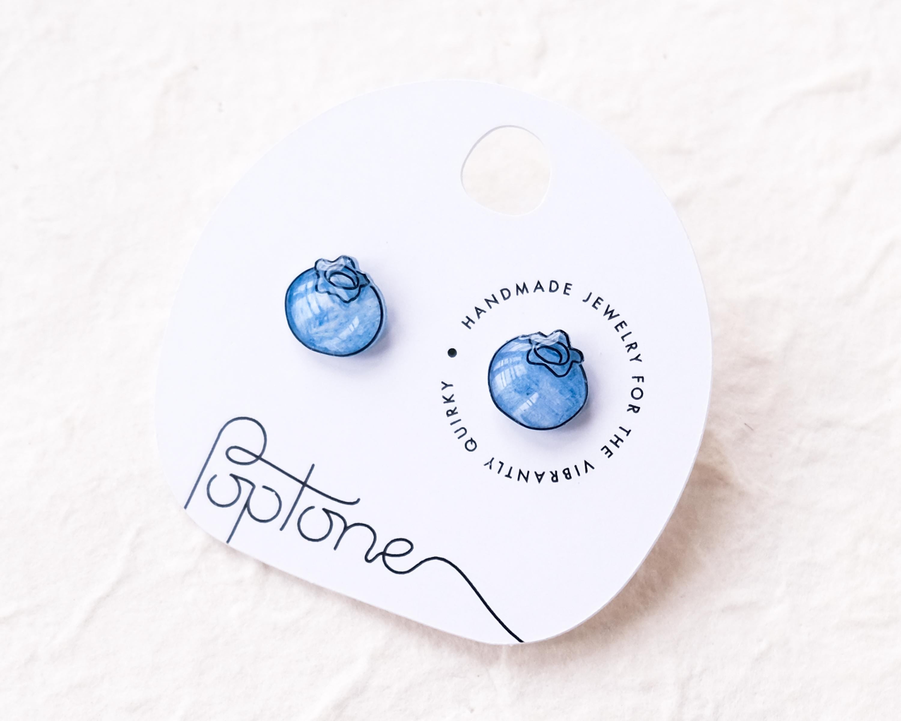 a pair of blue earrings sitting on top of a white box