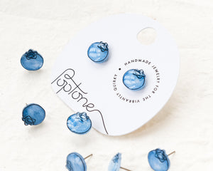 a pair of blue earrings sitting on top of a white box