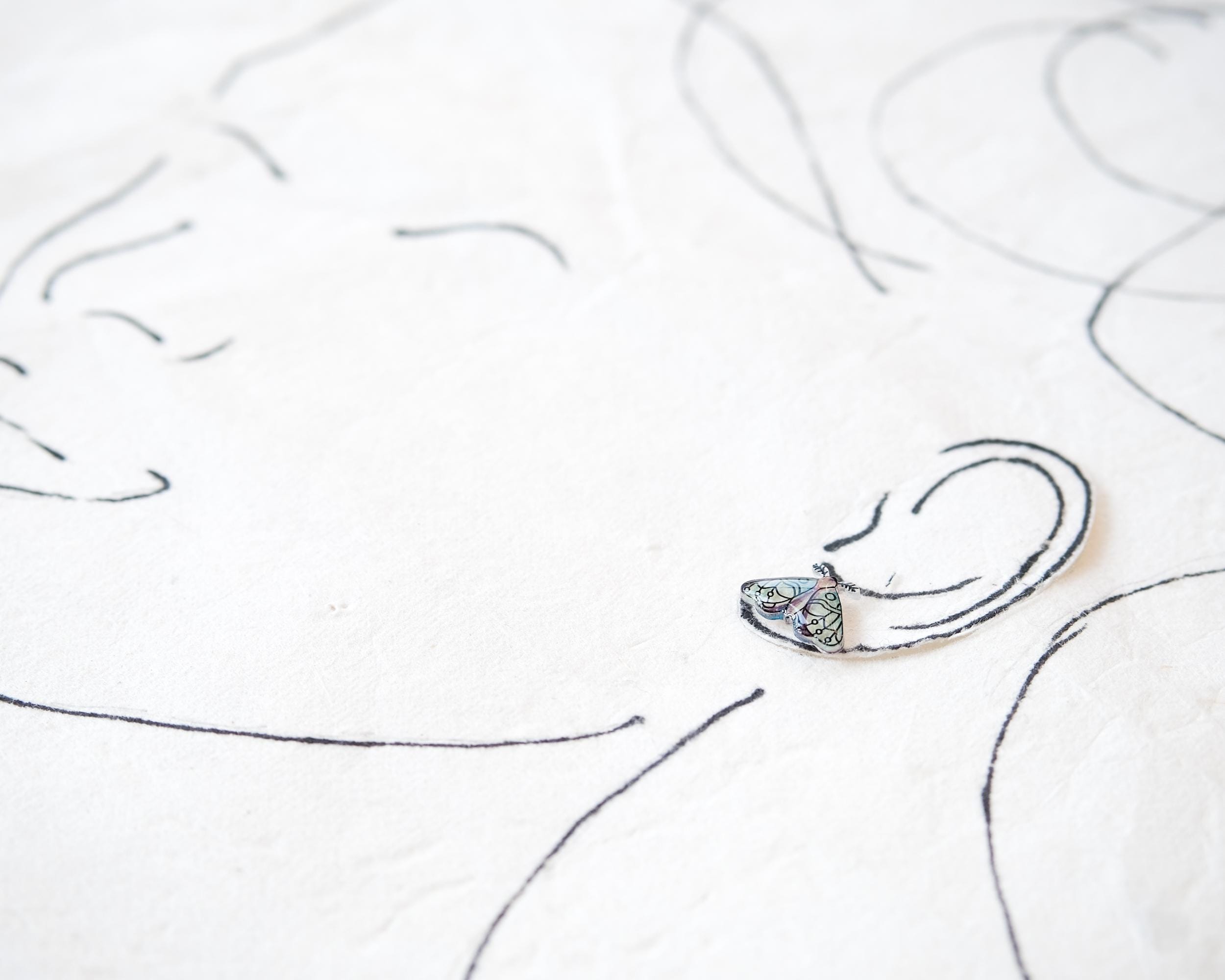 a close-up view of a small, intricately designed earring with a floral pattern.