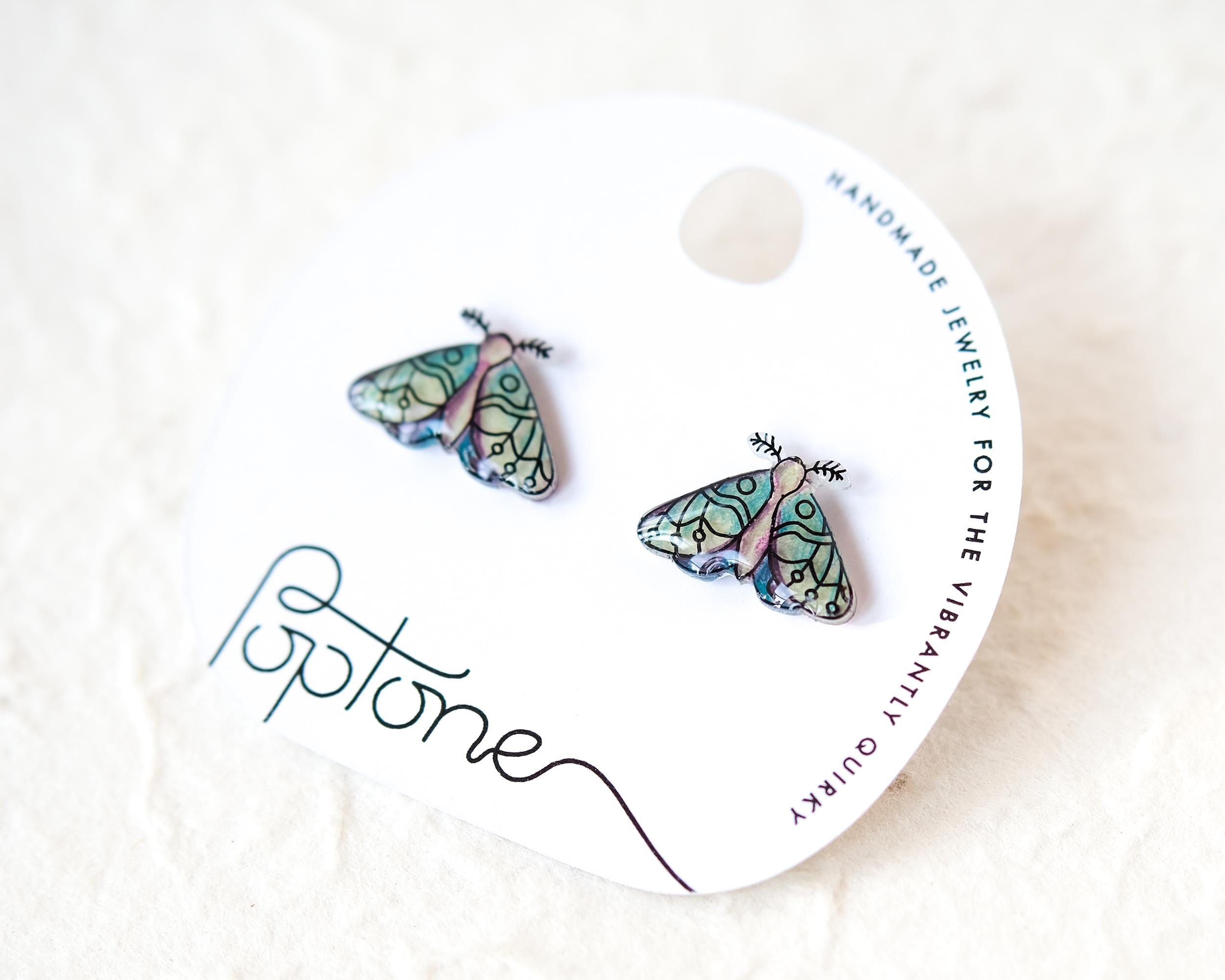 a pair of earrings with a butterfly design, placed on a white background.