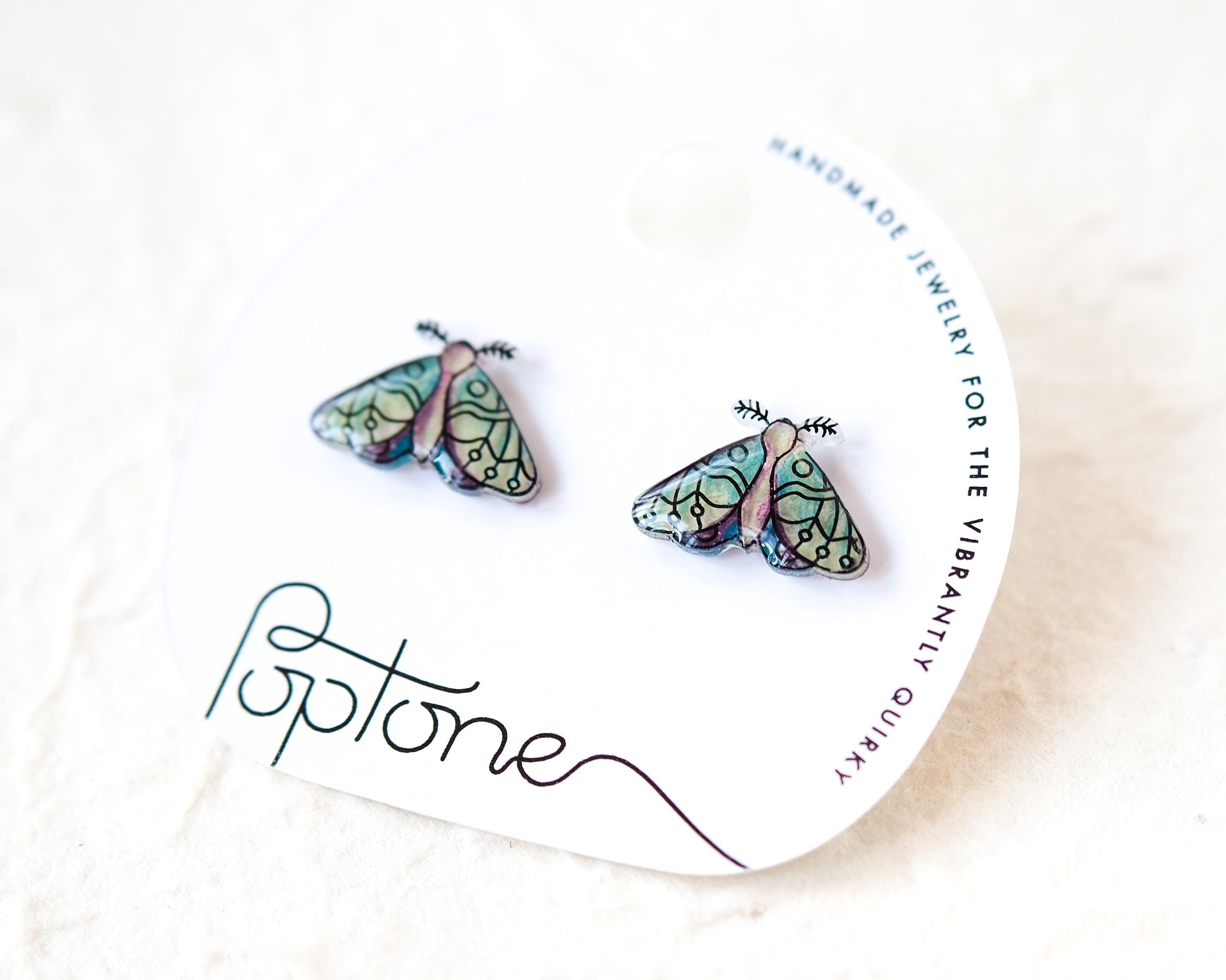A pair of earrings with butterfly designs, as shown on the packaging.