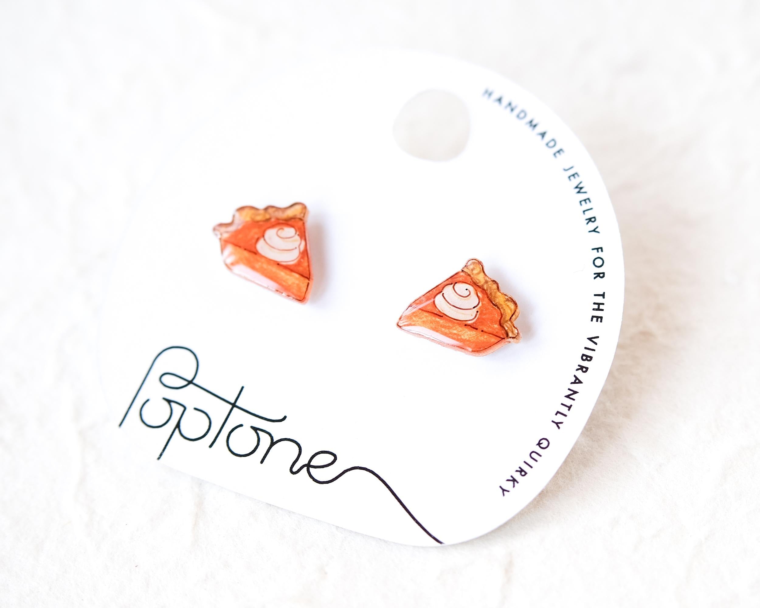 a pair of earrings with a pumpkin pie design, displayed on a white background.