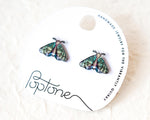 Load image into Gallery viewer, a pair of earrings with butterfly designs, placed on a white circular card with text and logos.
