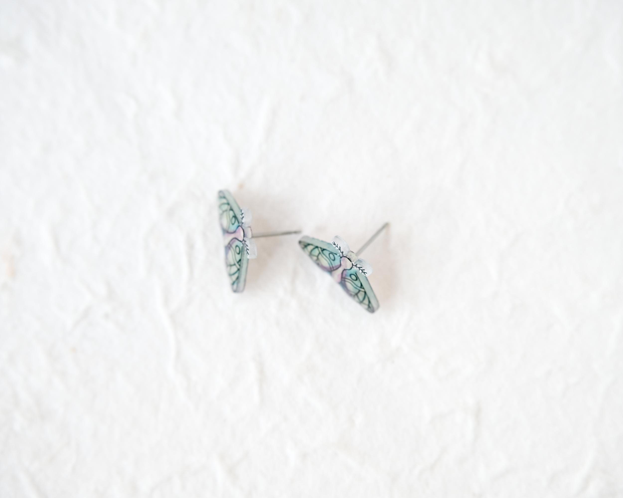A pair of earrings with butterfly designs on a white background.