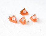 Load image into Gallery viewer, A group of four small, orange-colored earrings with white swirl designs on them, arranged on a white surface.
