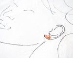 Load image into Gallery viewer, a close-up view of a person&#39;s face, with a small orange object, possibly an earring, placed on the right side of the frame.
