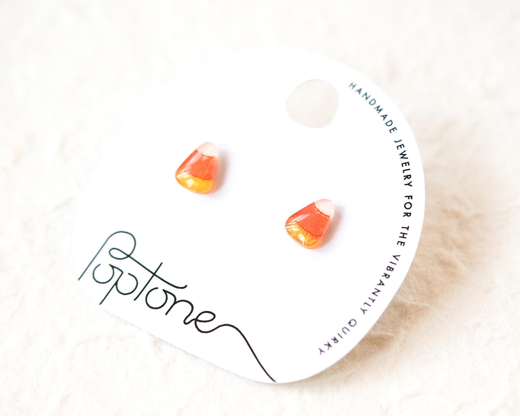 a pair of earrings, each with a candy corn-shaped design, displayed on a white background.