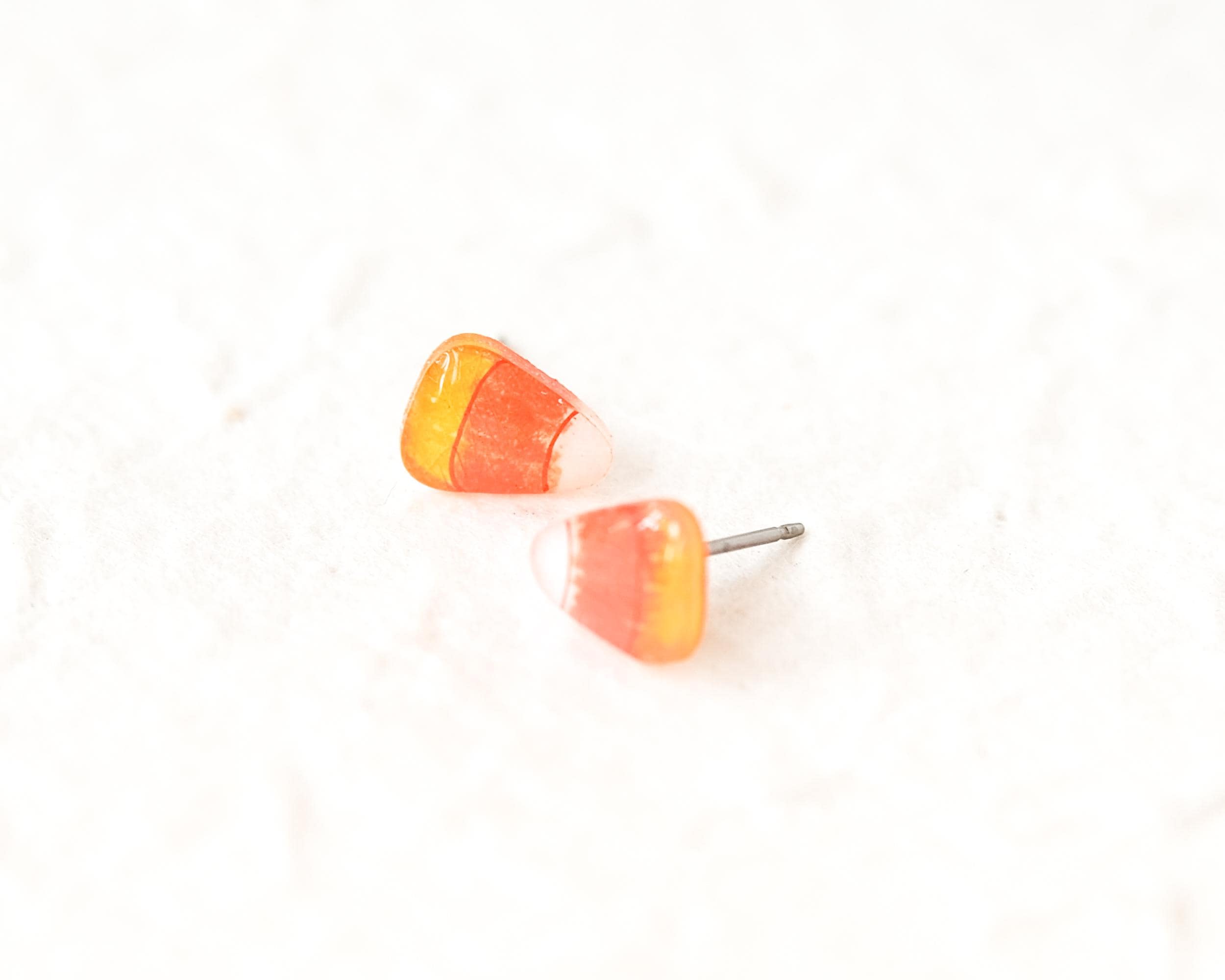 A pair of candy corn earrings is shown against a white background.