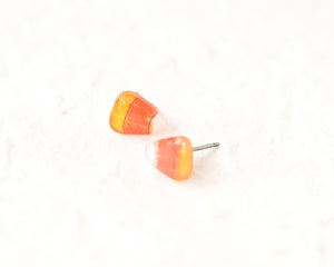 A pair of candy corn earrings is shown against a white background.