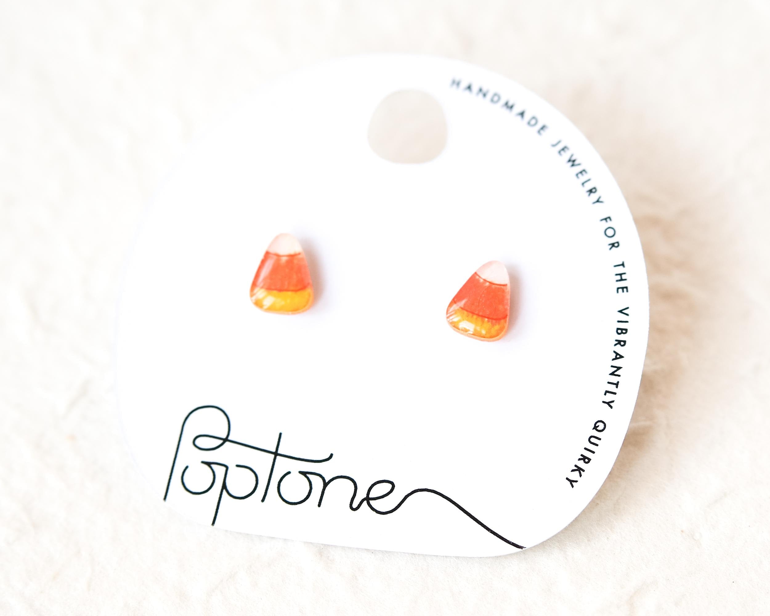 a pair of earrings made of candy corn, displayed on a white background.