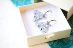 Load image into Gallery viewer, White and Silver Elegant Moth Earrings on Silver Hinged 12 mm Huggie Hoops
